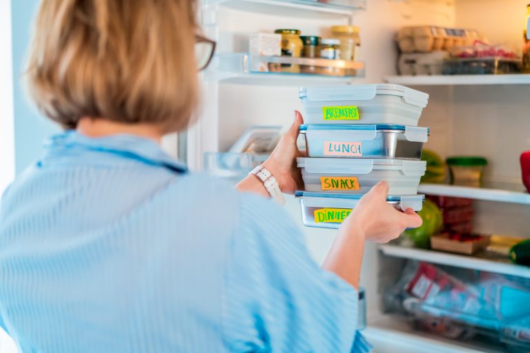 Working parents placing her batched cooked meals in the fridge for later in the week
