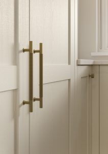 Kitchen with Nola door in Taupe Grey by The Kitchen Depot, featuring an island with bar stools, light cabinetry, and gold accents.