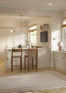 Kitchen with Nola door in Taupe Grey by The Kitchen Depot, featuring an island with bar stools, light cabinetry, and gold accents.