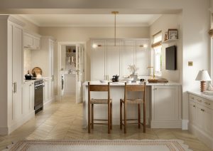 Kitchen with Nola door in Taupe Grey by The Kitchen Depot, featuring an island with bar stools, light cabinetry, and gold accents.